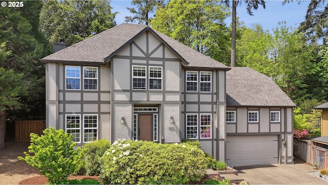 english style home with stucco siding, a shingled roof, fence, and concrete driveway