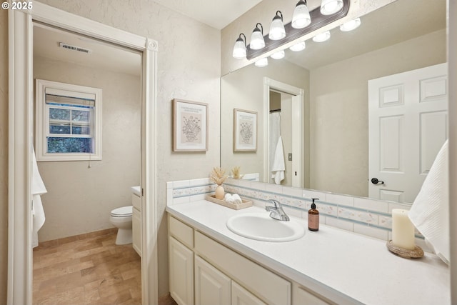 bathroom with toilet, vanity, and wood finished floors