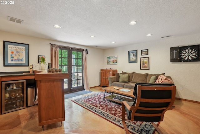 living room featuring a textured ceiling, beverage cooler, recessed lighting, baseboards, and a bar