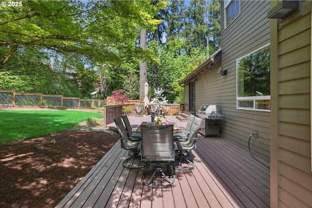 wooden deck with outdoor dining area, grilling area, and view of wooded area