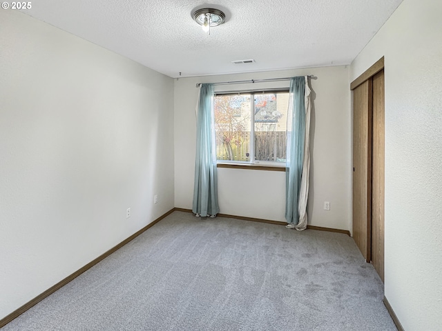 empty room featuring a textured ceiling and light carpet