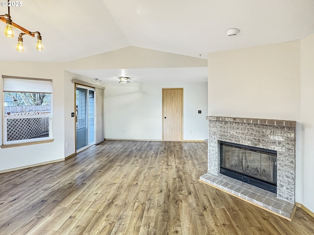 unfurnished living room with a fireplace, vaulted ceiling, and wood-type flooring