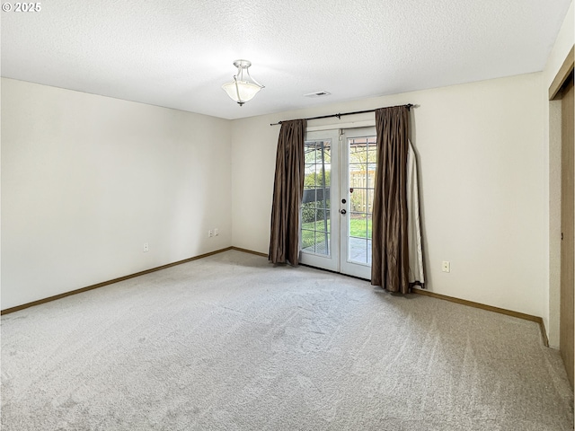 spare room featuring a textured ceiling, french doors, and carpet