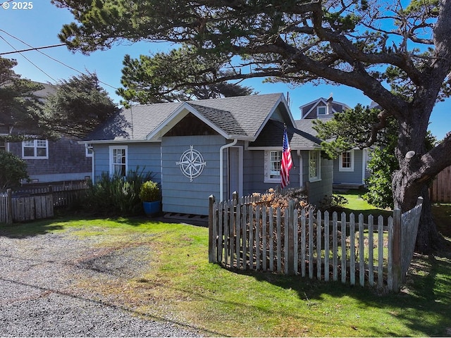 view of front of home with fence, a front lawn, and roof with shingles