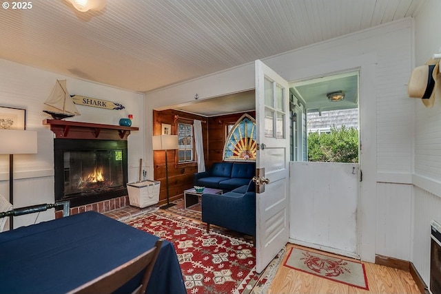 interior space with wood walls, wood finished floors, and a glass covered fireplace