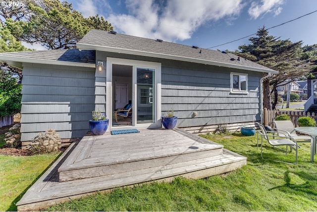 rear view of house with a yard, a shingled roof, and a wooden deck