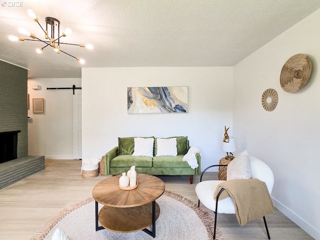 4145 SE Grant St, Portland, OR 97214 - living room featuring light wood finished floors, baseboards, a textured ceiling, a chandelier, and a barn door
