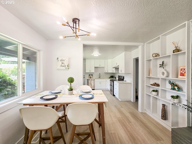 4145 SE Grant St, Portland, OR 97214 - dining area with a chandelier, light wood-style floors, and a textured ceiling