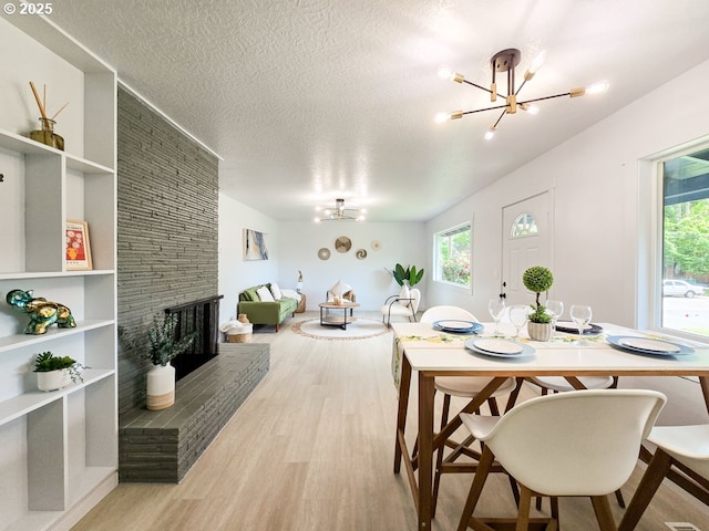 4145 SE Grant St, Portland, OR 97214 - dining room featuring a chandelier, wood finished floors, a textured ceiling, and a brick fireplace