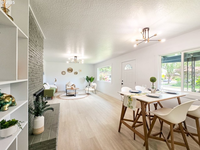 4145 SE Grant St, Portland, OR 97214 - dining room featuring a chandelier, wood finished floors, a textured ceiling, baseboards, and a large fireplace