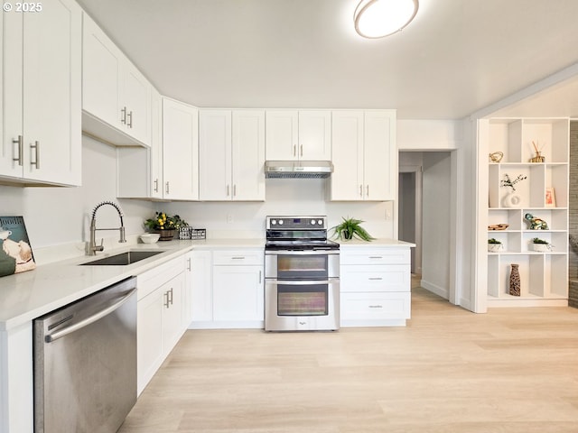 4145 SE Grant St, Portland, OR 97214 - kitchen with appliances with stainless steel finishes, under cabinet range hood, a sink, light countertops, and light wood-type flooring
