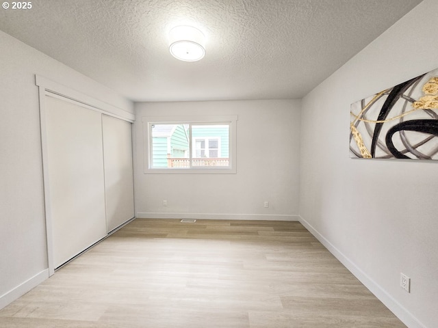 4145 SE Grant St, Portland, OR 97214 - unfurnished bedroom featuring light wood-style flooring, a textured ceiling, a closet, and baseboards