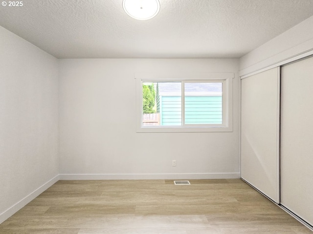 4145 SE Grant St, Portland, OR 97214 - unfurnished bedroom featuring light wood finished floors, a closet, baseboards, and a textured ceiling