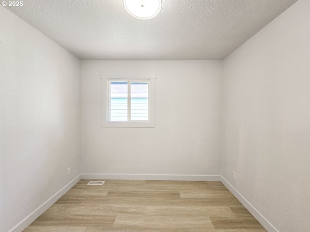 4145 SE Grant St, Portland, OR 97214 - empty room with light wood-style flooring, a textured ceiling, and baseboards