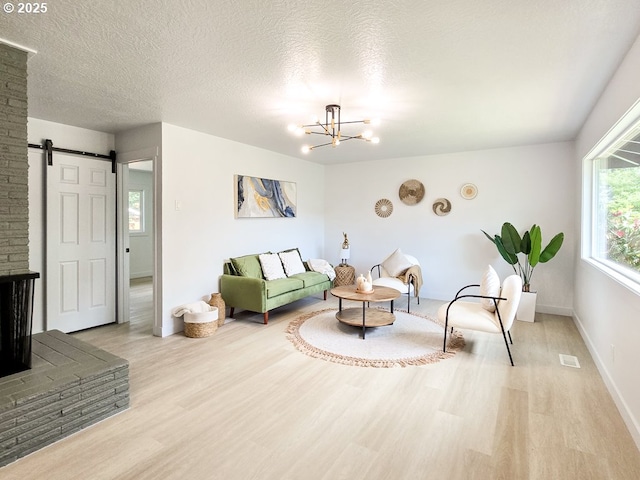 4145 SE Grant St, Portland, OR 97214 - living area with light wood-style floors, a barn door, a chandelier, baseboards, and a textured ceiling