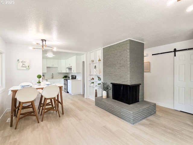 4145 SE Grant St, Portland, OR 97214 - dining area with light wood-style floors, a barn door, a textured ceiling, a chandelier, and baseboards