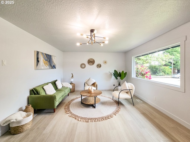 4145 SE Grant St, Portland, OR 97214 - living area featuring wood finished floors, a chandelier, a textured ceiling, and baseboards