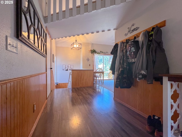 foyer with wood-type flooring, wooden walls, and a chandelier