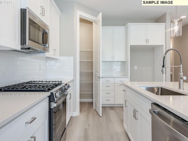 908 NW 178th Way, Ridgefield, WA 98642 - kitchen featuring stainless steel appliances, a sink, light wood-style flooring, white cabinetry, and light countertops