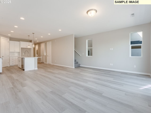 908 NW 178th Way, Ridgefield, WA 98642 - unfurnished living room featuring stairway, baseboards, recessed lighting, light wood finished floors, and a sink