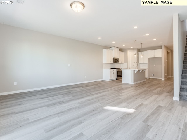 908 NW 178th Way, Ridgefield, WA 98642 - unfurnished living room featuring stairs, light wood-type flooring, baseboards, a sink, and recessed lighting