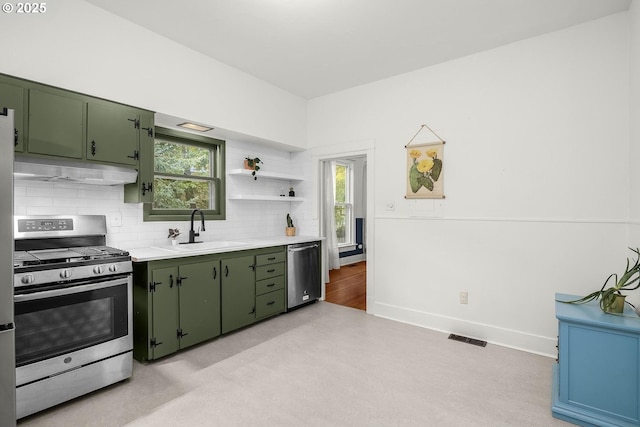 kitchen featuring stainless steel appliances, sink, green cabinets, and backsplash