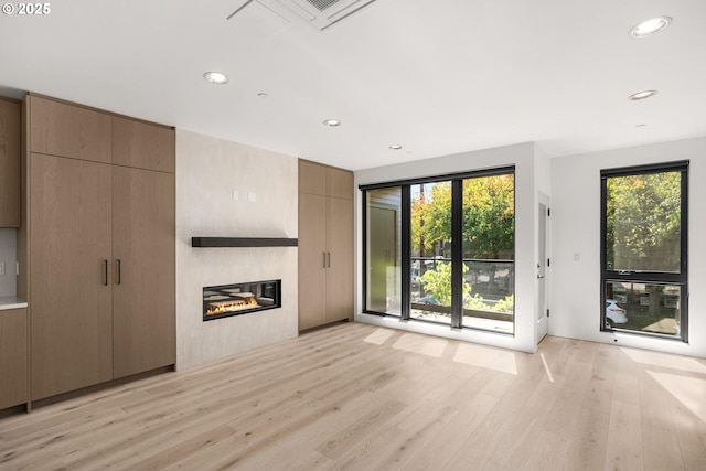 unfurnished living room with a large fireplace and light hardwood / wood-style flooring