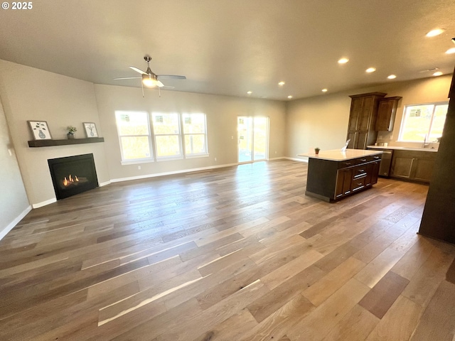 unfurnished living room with hardwood / wood-style flooring, ceiling fan, and a healthy amount of sunlight