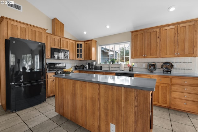 kitchen featuring decorative backsplash, vaulted ceiling, a kitchen island, and black appliances