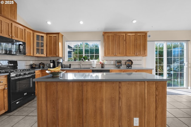 kitchen featuring a kitchen island, plenty of natural light, light tile patterned floors, and black appliances