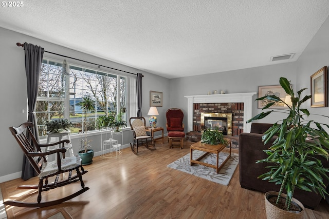 living room featuring a textured ceiling, a fireplace, and light hardwood / wood-style floors