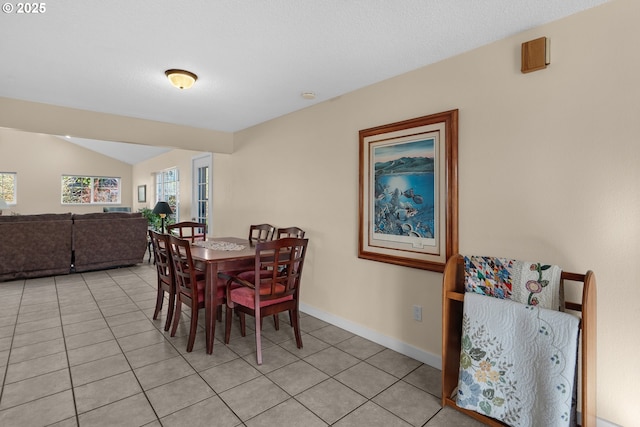 tiled dining room featuring vaulted ceiling