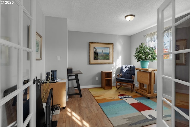 office featuring light hardwood / wood-style flooring, french doors, and a textured ceiling