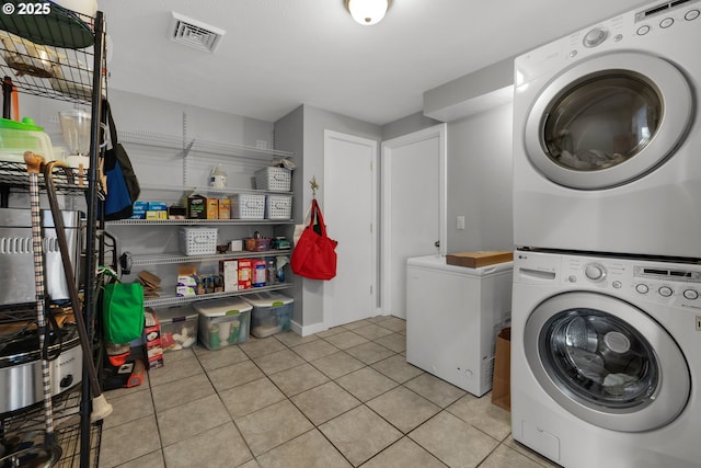 clothes washing area with stacked washer / dryer and light tile patterned floors