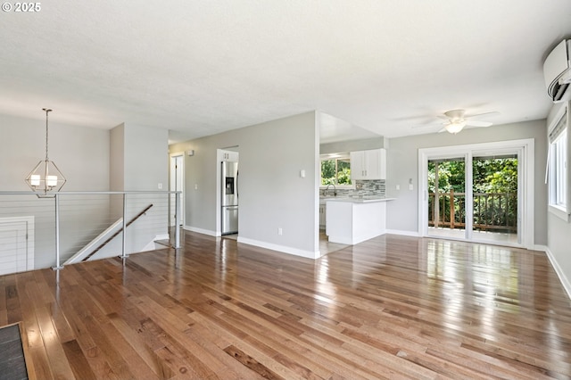 704 SE 207th Ave, Gresham, OR 97030 - unfurnished living room featuring light wood-style floors, a chandelier, a ceiling fan, and a wall unit AC