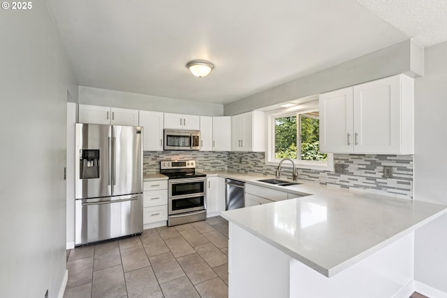 704 SE 207th Ave, Gresham, OR 97030 - kitchen with stainless steel appliances, a peninsula, light countertops, tasteful backsplash, and white cabinetry