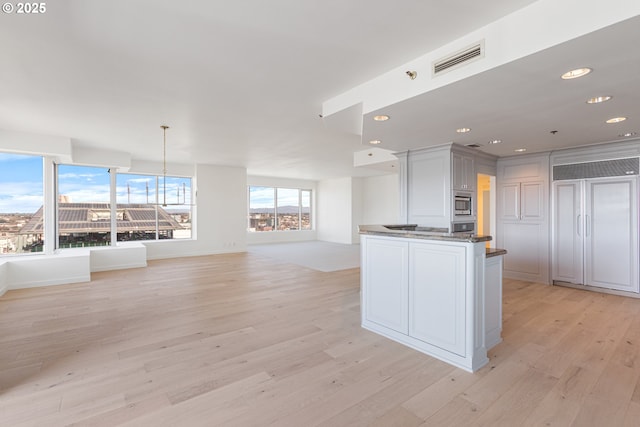 kitchen with visible vents, open floor plan, built in appliances, light wood-style floors, and white cabinetry