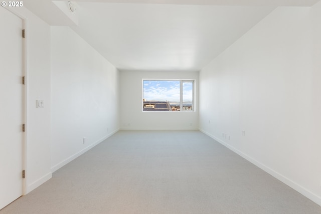 spare room featuring baseboards and light colored carpet