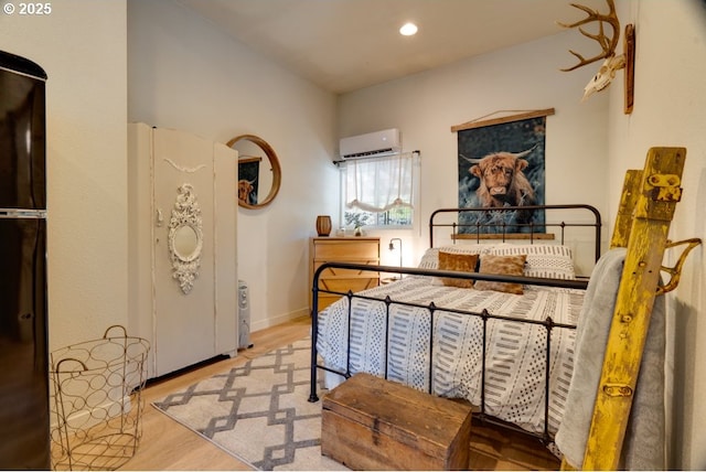 bedroom featuring light hardwood / wood-style floors and an AC wall unit