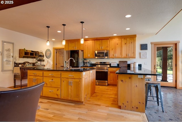 kitchen featuring decorative light fixtures, stainless steel appliances, an island with sink, and a breakfast bar