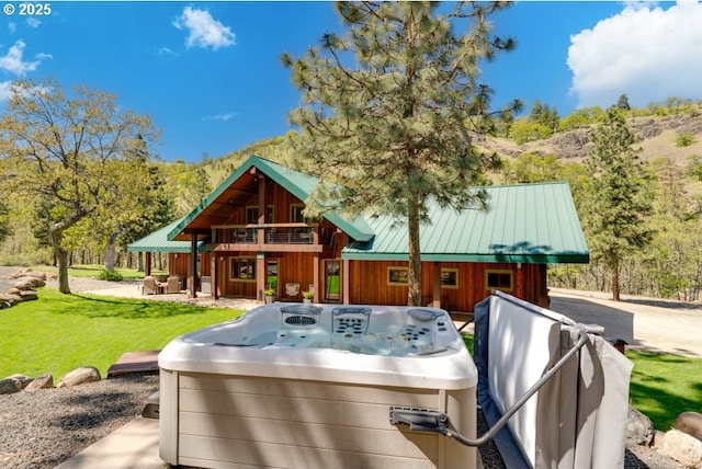 exterior space with a hot tub, a patio area, and a front lawn