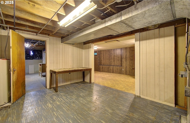 finished basement featuring water heater and wooden walls