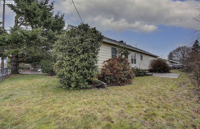 view of property exterior featuring a lawn, a patio area, and fence