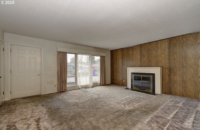 unfurnished living room featuring carpet floors, a fireplace with flush hearth, and wooden walls