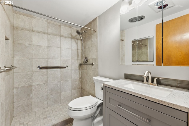bathroom with toilet, a tile shower, and vanity