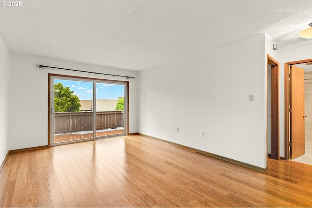 spare room featuring a textured ceiling, wood finished floors, and baseboards