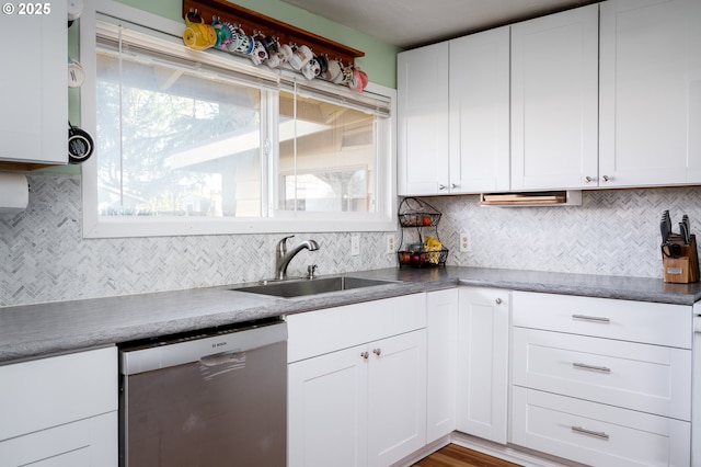 kitchen with white cabinetry, stainless steel dishwasher, sink, and backsplash