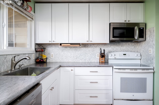 kitchen with stainless steel appliances, sink, white cabinets, and backsplash