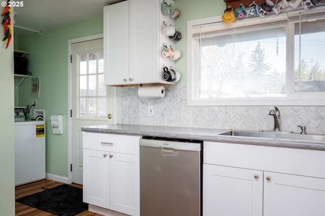 kitchen with white cabinetry, stainless steel dishwasher, washer / dryer, and sink