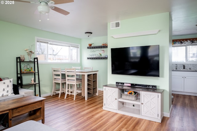 living room featuring sink, light hardwood / wood-style flooring, ceiling fan, and plenty of natural light